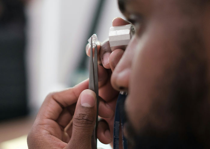 A person closely examines an object using a measuring tool, focusing on precision and detail.