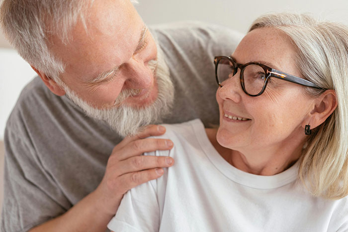 Elderly couple smiling at each other, capturing a tender moment and displaying affection.