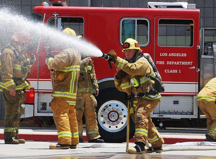 Firefighters in action with a Los Angeles fire truck, highlighting female leadership in firefighting.