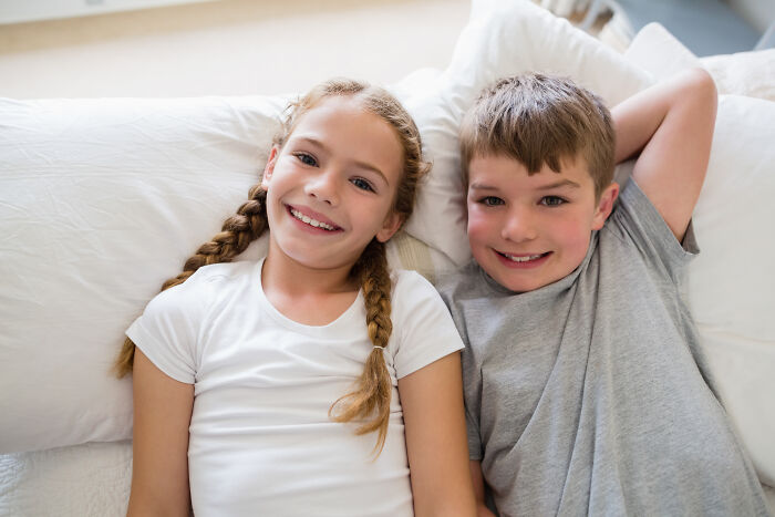 Two smiling children lying on pillows, representing a family home setting.