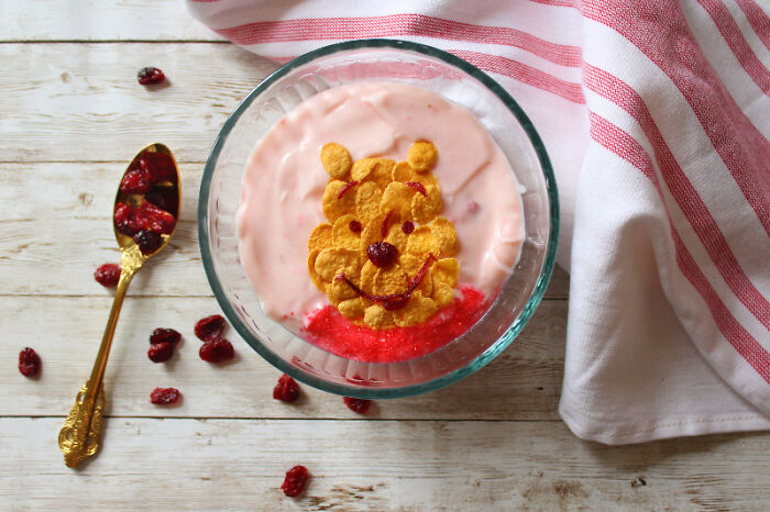 Cartoon-inspired food art with fresh ingredients in a bowl, next to a decorative spoon and cloth.