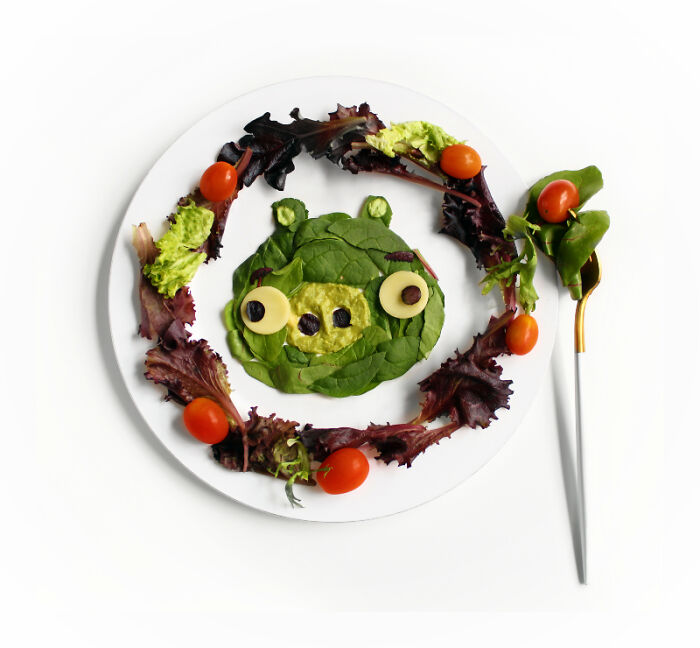 Playful food art design using fresh ingredients inspired by cartoons, featuring a character made of leafy greens and tomatoes.