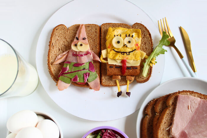 Playful food art with fresh ingredients, depicting cartoon characters on bread slices with eggs and juice nearby.