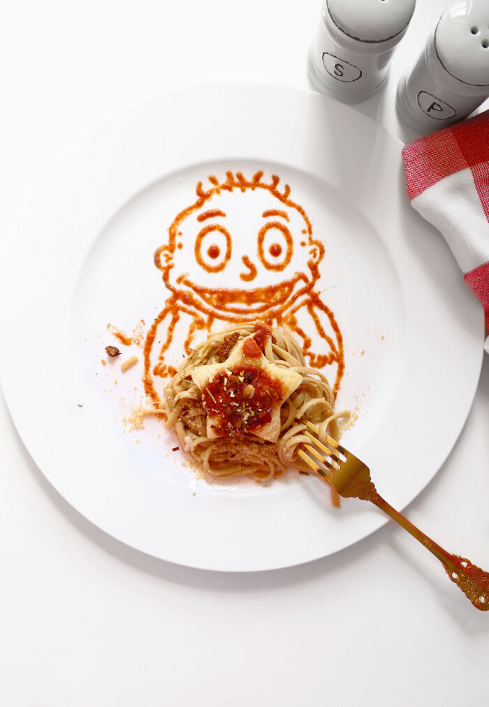 Cartoon-inspired food art with pasta and sauce creating a playful design on a white plate.