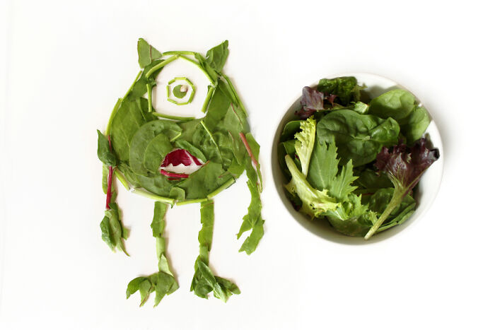 Cartoon-inspired food art using fresh ingredients to create a character with leafy greens next to a bowl of salad.