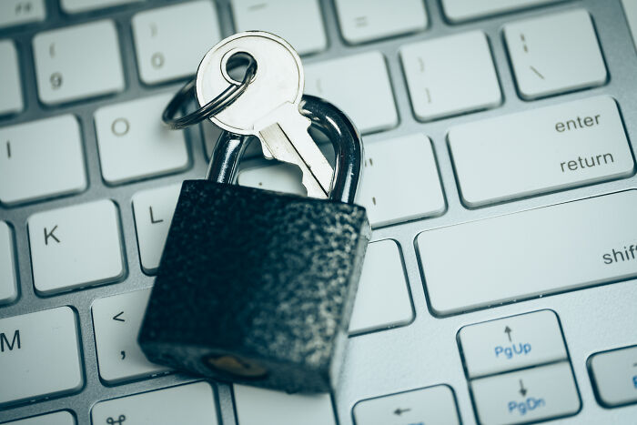 A padlock and key resting on a keyboard, symbolizing cybersecurity and protection against scams.