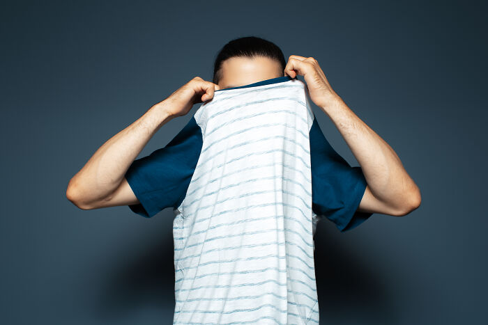 Person creatively hiding face with shirt, symbolizing a dramatic job exit.