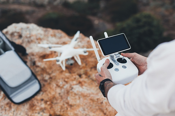 Man controlling a drone in rocky terrain, illustrating a successful business venture.