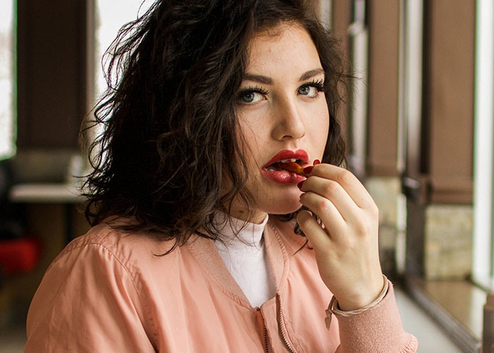 Woman in pink jacket eating chips, linked to vegetarian food thief narrative.