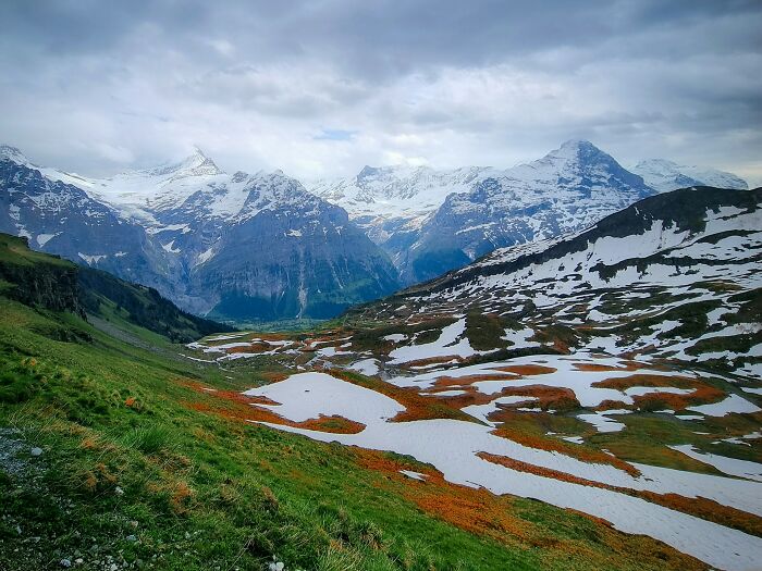 Snow-capped mountains and green hills under a cloudy sky in the Tuscany region of Italy.