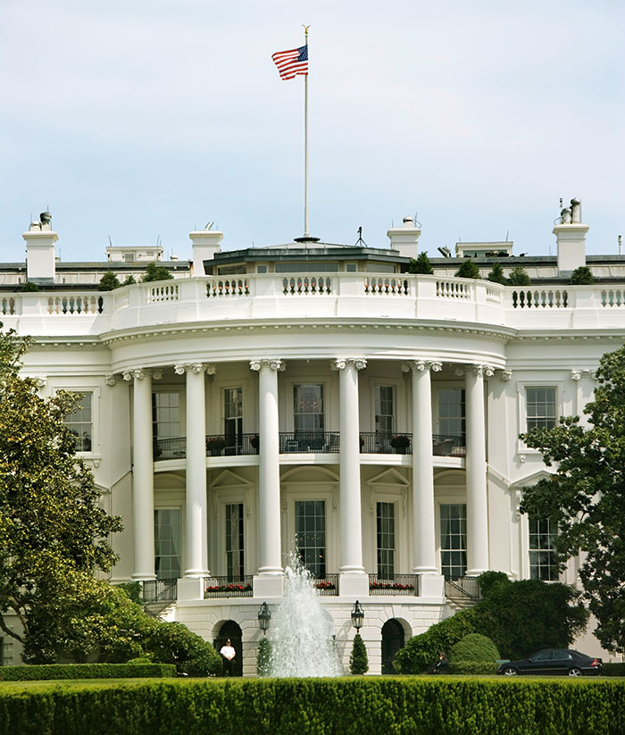 White House exterior with American flag flying on top, symbolizing political leadership.