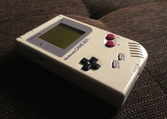 A vintage Game Boy on a textured brown surface, highlighting retro technology shared with grandparents.