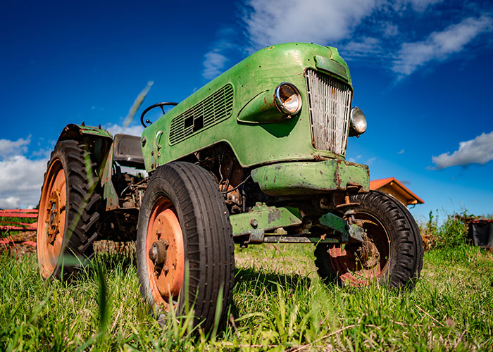 A vintage green tractor on a sunny day, representing wisdom shared between older people and grandparents.