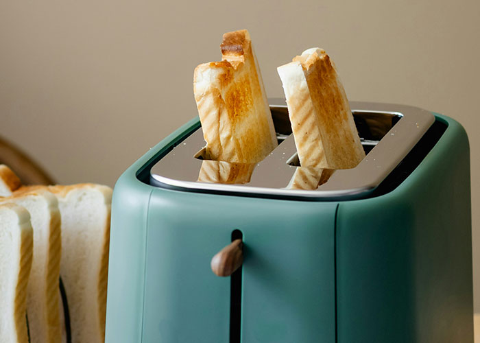 Green toaster with toasted bread slices, a relatable moment for older people sharing technology tips with grandparents.