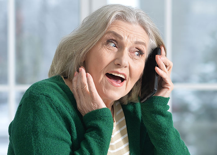 Older person excitedly talking on a smartphone, learning new things in a cheerful way.