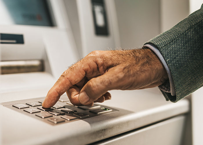 Older person using an ATM, showcasing what they can teach grandparents about technology.