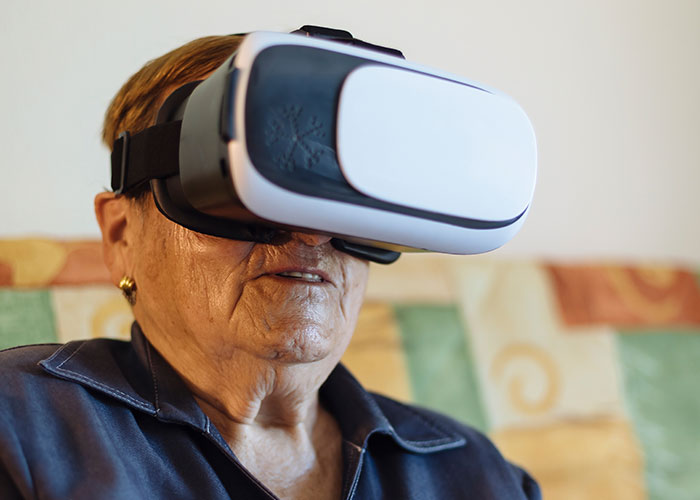 Older person using VR headset, experiencing modern technology in a cozy room, highlighting adorable teaching moments.