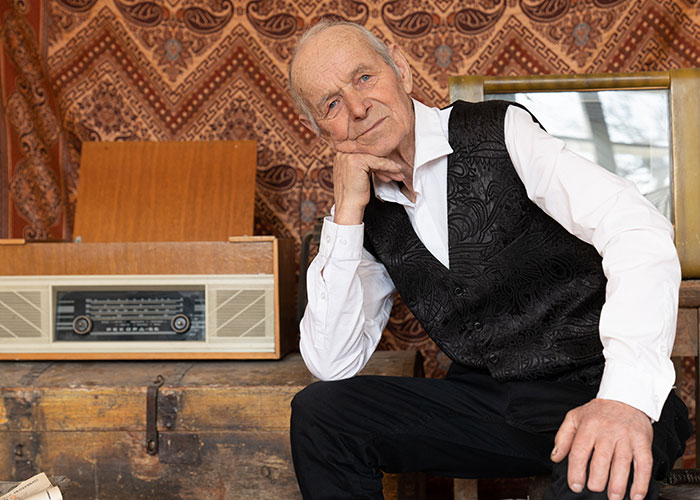 Older person sitting thoughtfully by a vintage radio, embodying wisdom shared with grandparents.