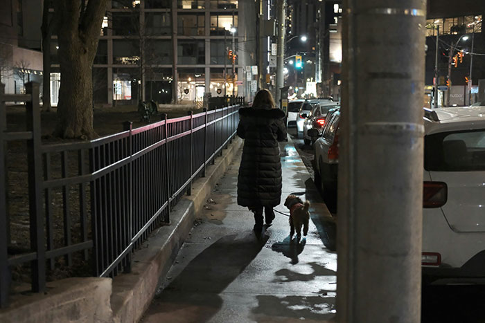 Person walking a dog on a dimly lit city street at night, illustrating creepy situations involving men unnoticed.