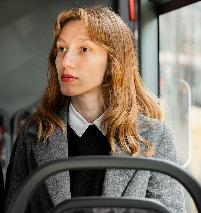 A woman sitting on a bus, looking outside, emphasizing personal space in public transport.