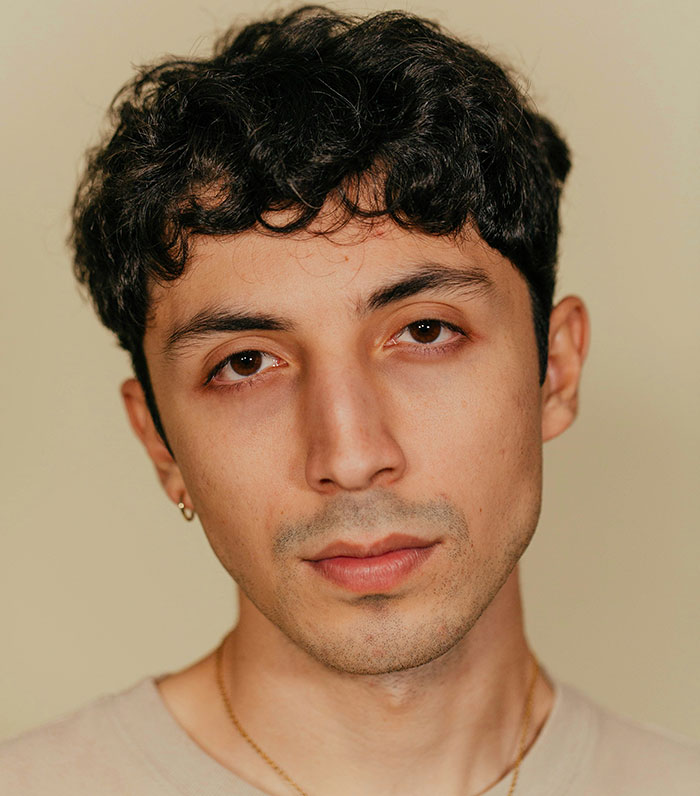 Man with curly hair looking directly at the camera, related to creepy behaviors theme.