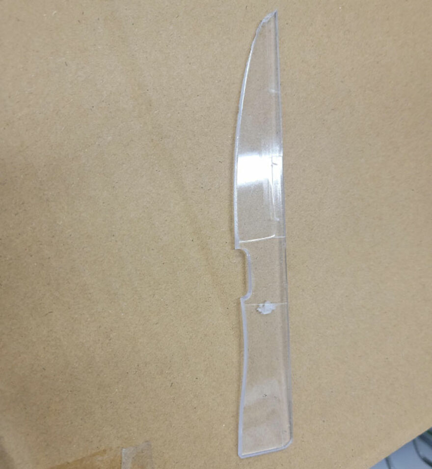 Transparent plastic knife resembling a real knife on a cardboard surface.