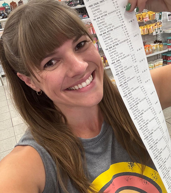 Smiling woman holding a long receipt related to thrifted boots gift for MIL.