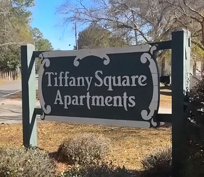 Sign for Tiffany Square Apartments surrounded by trees.