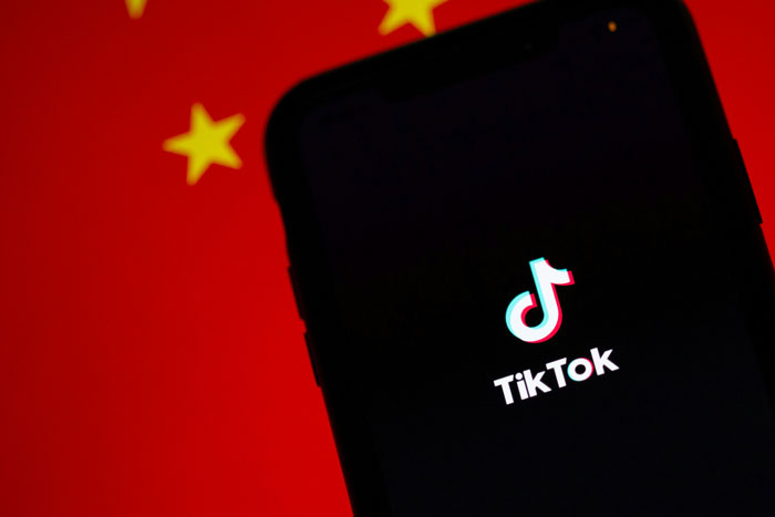 TikTok app on smartphone screen against Chinese flag backdrop.