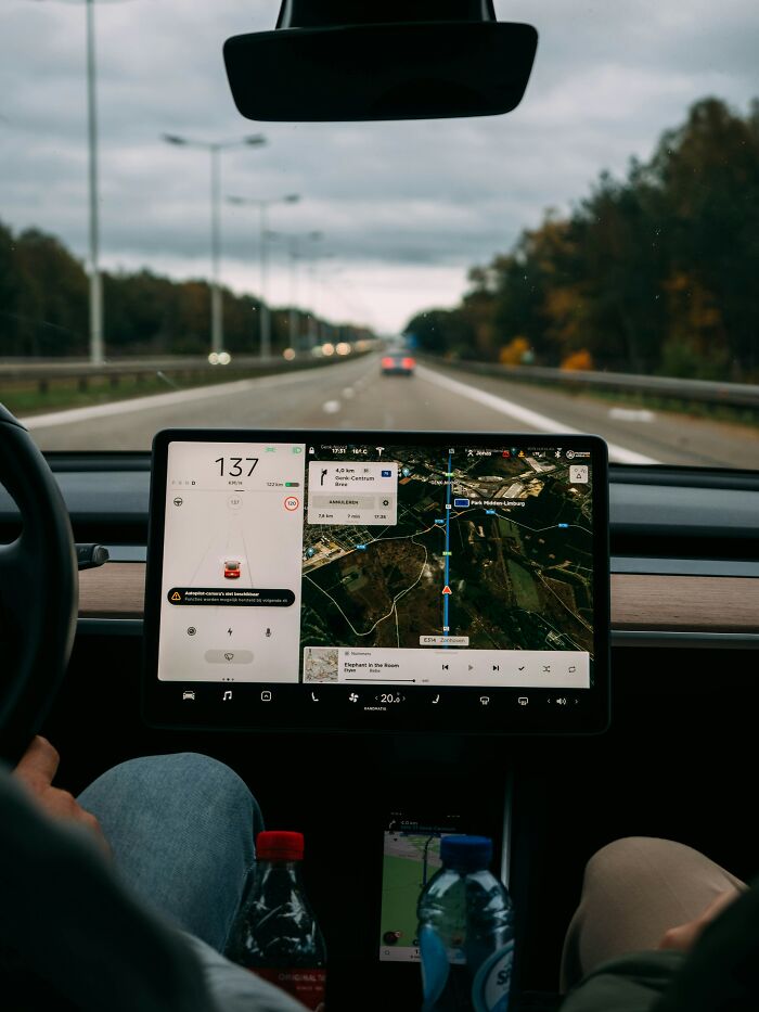 Car dashboard with navigation screen displaying a route, showcasing new facts through a digital interface.