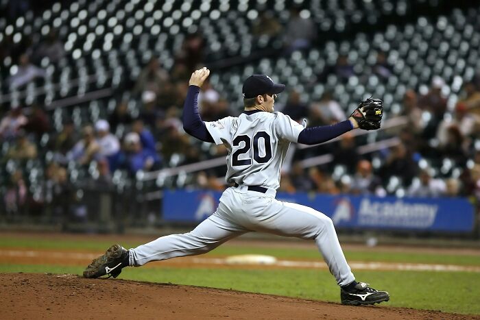 Baseball player in action on the field, wearing a number 20 jersey, amidst a sparsely crowded stadium.