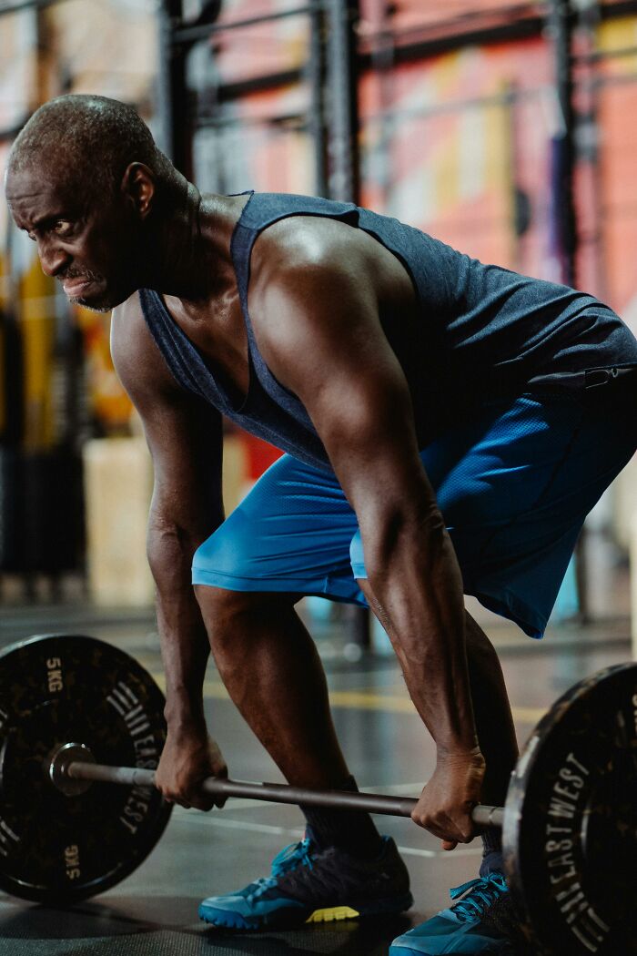 Man lifting weights in a gym, demonstrating strength and focus.