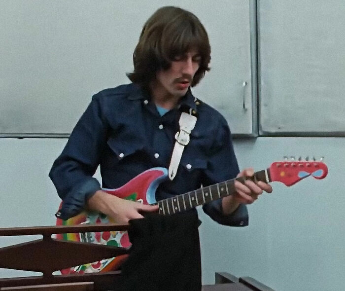 Person playing a colorful electric guitar, wearing a dark shirt, possibly sharing new facts from a "Today I Learned" moment.