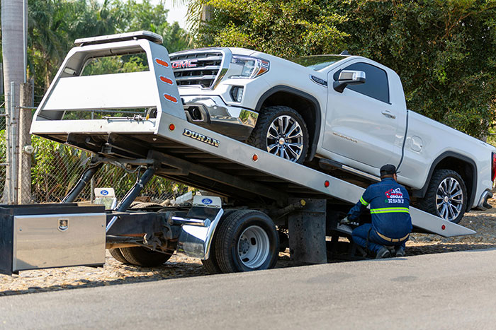 Tow truck loading a white pickup truck, highlighting a towing company scenario.