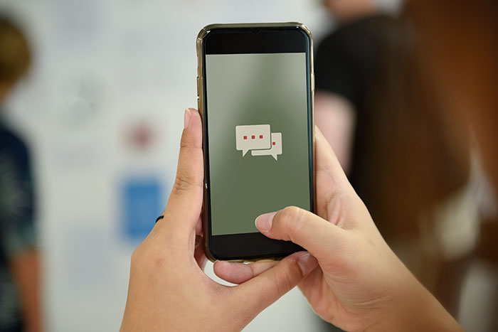 Person holding phone displaying chat bubbles, related to towing company conflict over payment.