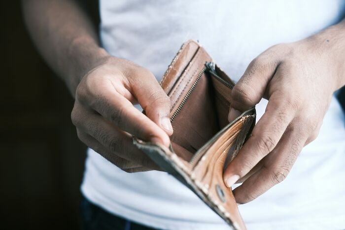 Person holding an empty wallet, suggesting financial loss or scam.