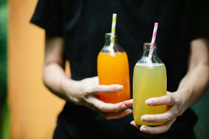 Person holding two bottles of sugary drinks, representing toxic things for the body.