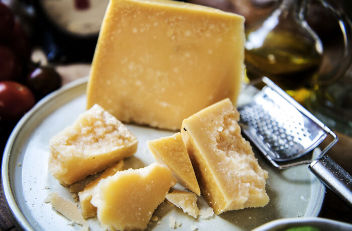 A plate of aged cheese with a grater, showcasing one of the toxic things for the body.