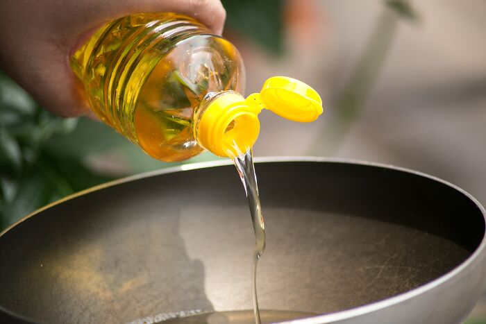 Pouring cooking oil into a pan, highlighting toxic things in the body.