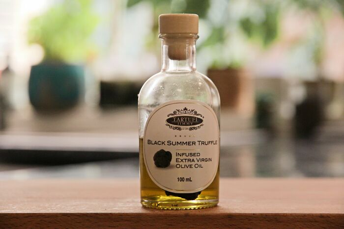 Bottle of black summer truffle infused olive oil on a wooden surface, related to toxic things body list.