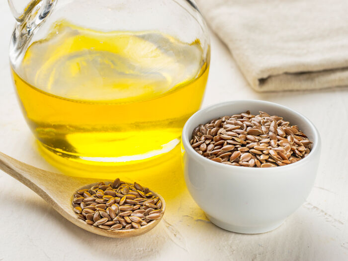 Bowl of flaxseeds and a jar of oil on a white surface, highlighting toxic things for the body.