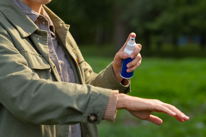 Person applying spray outdoors, focusing on toxic effects on the body.