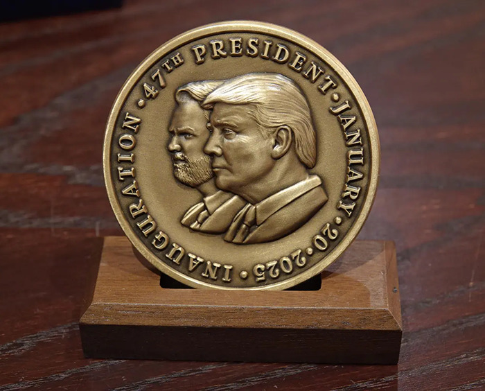 Inauguration medallion with engraved profiles on a wooden stand, related to VIP goodie bags.