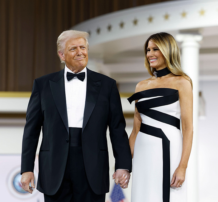 Couple holding hands in formal attire at a VIP event.