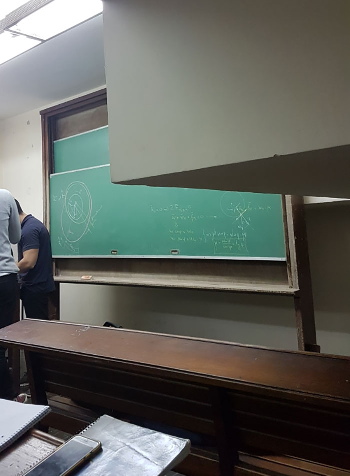 Unfortunate public interior design with an obstructed classroom chalkboard and seating.