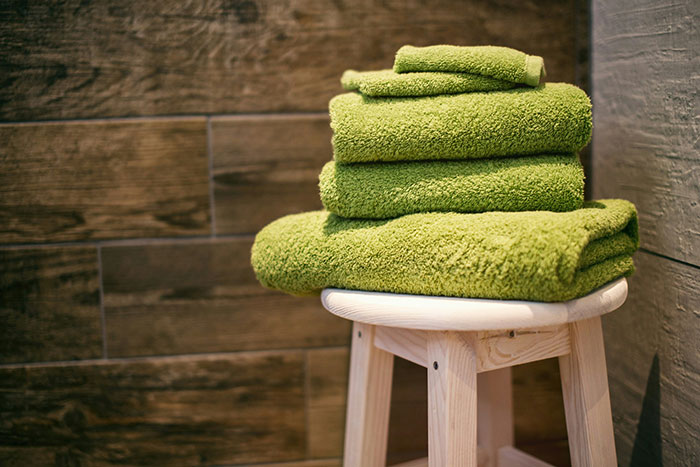 Green towels stacked on a stool in a hotel room, representing unspoken rules many follow when staying at a hotel.