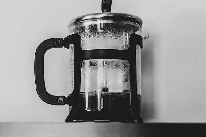 A French press coffee maker on a hotel room countertop, illustrating unspoken rules of hotel stays.