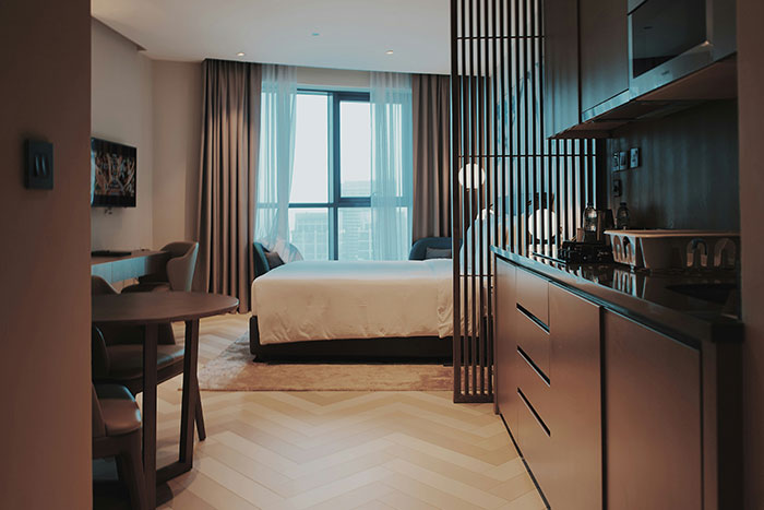 Modern hotel room interior with a large bed, window view, and stylish furnishings.