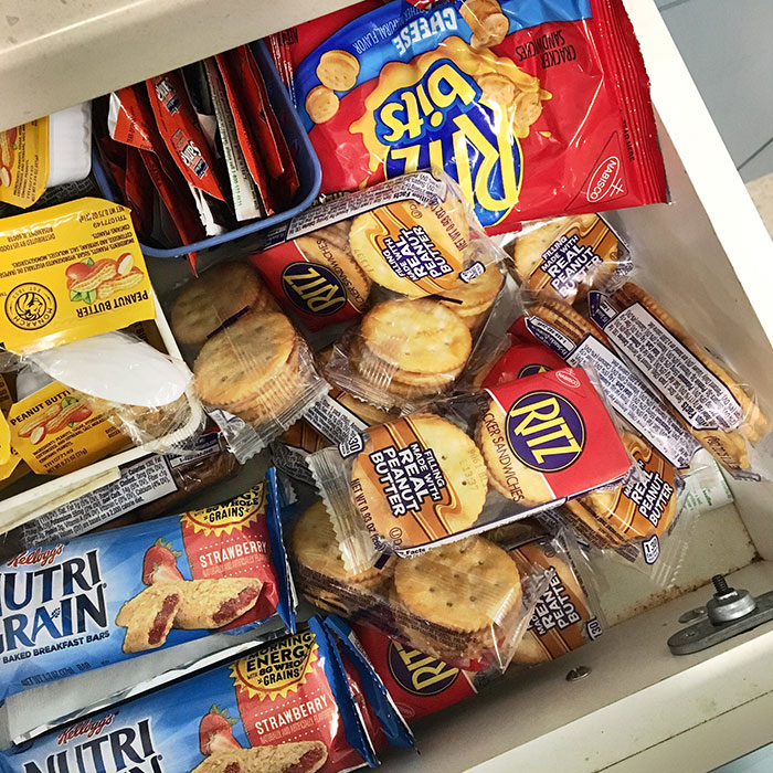 Assorted packaged snacks in a hotel room drawer, including crackers and bars.