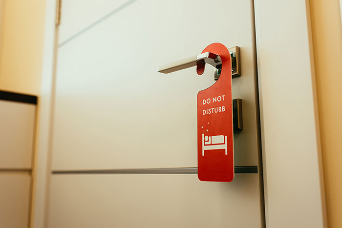 "Hotel room door with a 'Do Not Disturb' sign hanging, illustrating unspoken rules guests follow for privacy."